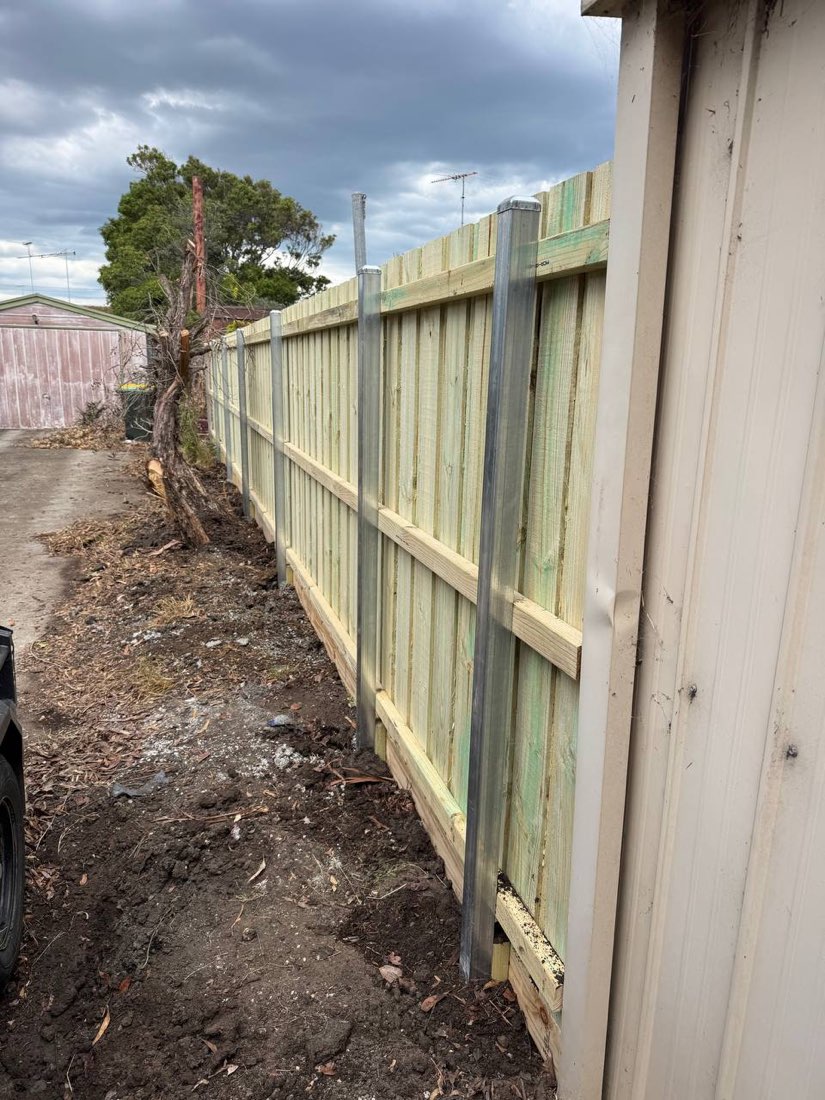 Galvanised steel-post paling fence with a timber plinth board down a side access in Indented Head