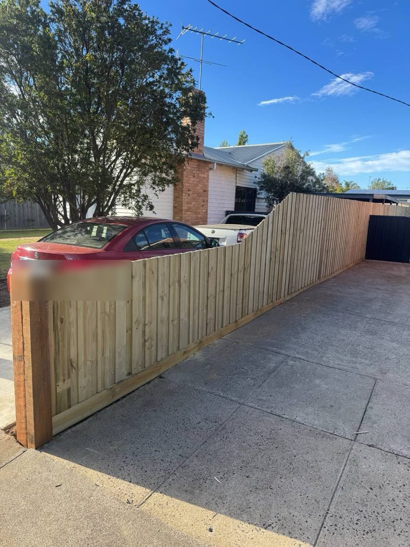 Low capped timber paling front-boundary fence along a driveway in Thomson